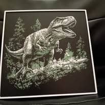 Tableau encadré en lithophane rétroéclairée montrant un tyrannosaure rugissant au milieu d'une forêt de sapins, en blanc sur fond noir.